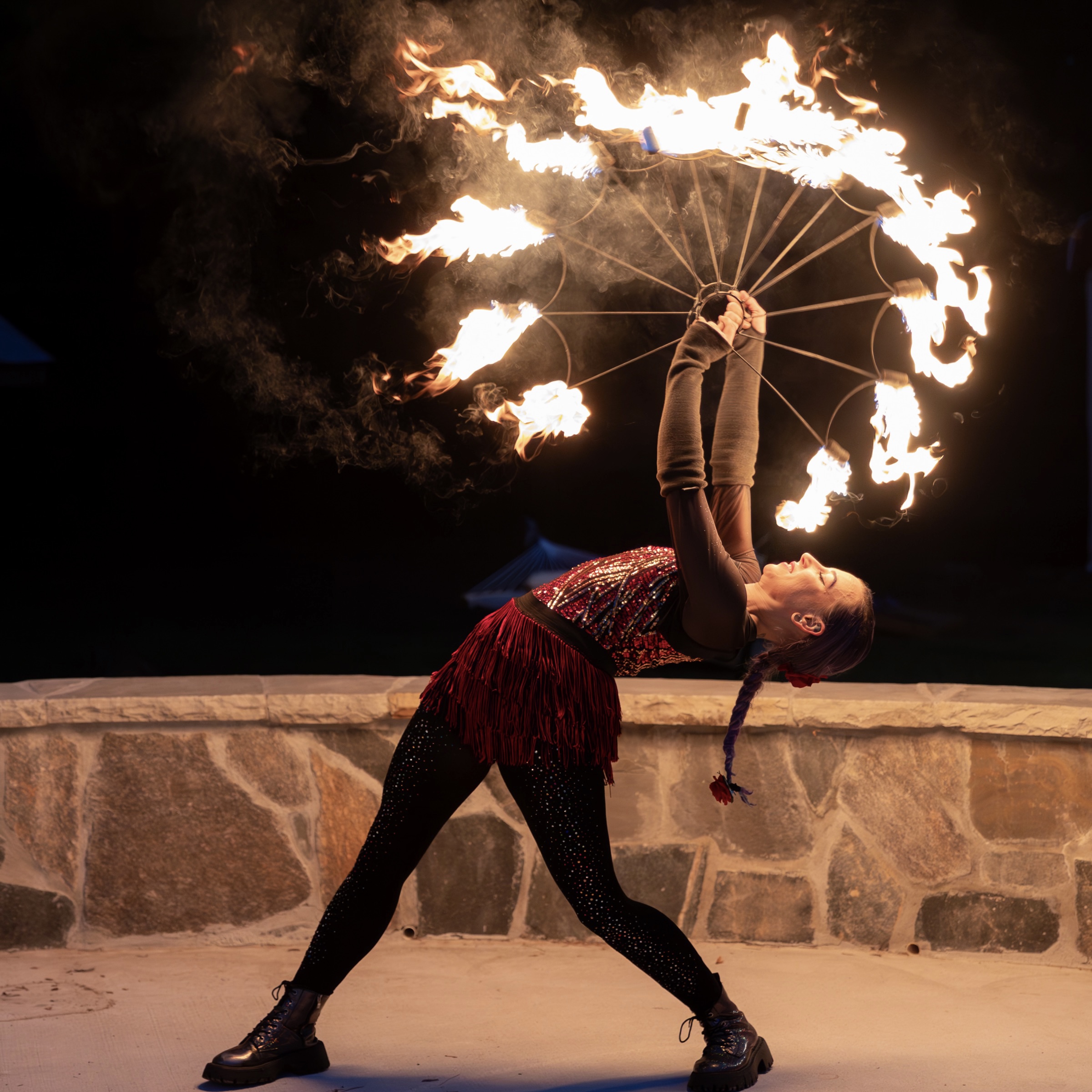 Fire dancer leaning back with big fire fans that form a circle of fire